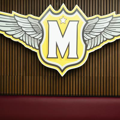 Sign featuring the letter 'M' enclosed in a shield with wings.