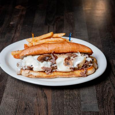 Philly cheesesteak sandwich with fries.