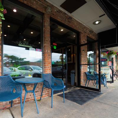 Outdoor seating with blue chairs and tables in front of Tre Sorelle restaurant.