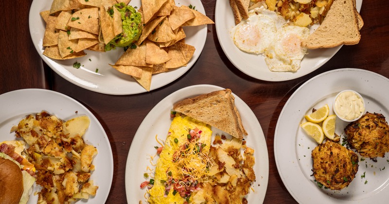 Egg dishes plated with toast and hash browns, served beside guacamole and chips