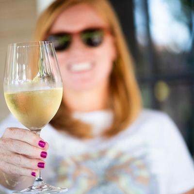 A person holding out a wine glass.