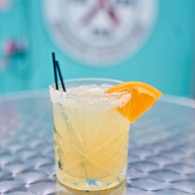 A margarita cocktail served in a rocks glass with a salted rim and an orange slice.