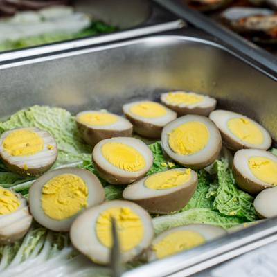Halved soy-marinated eggs rest on a bed of green napa cabbag.