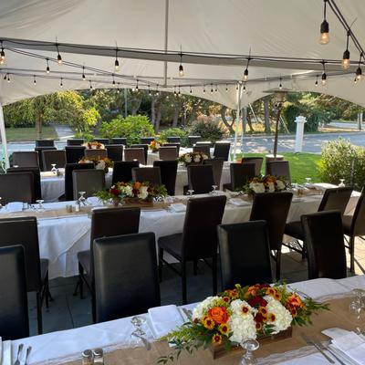 Outdoor event space with a large tent covering multiple dining tables.