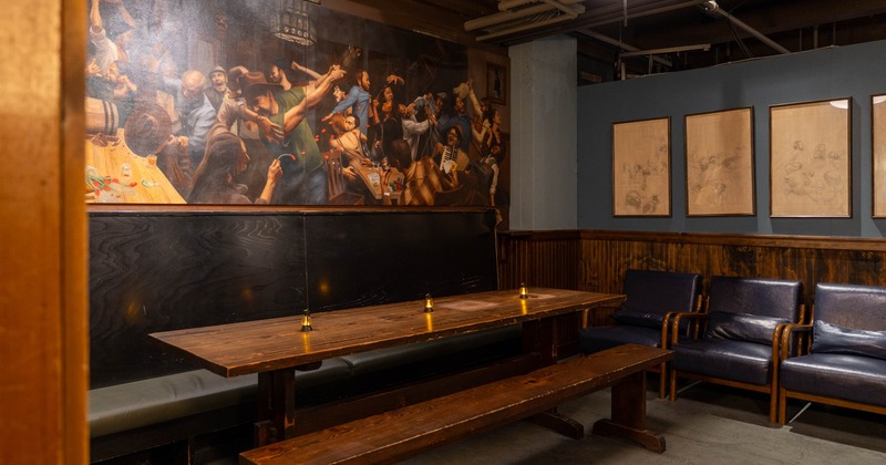 Interior space with a wooden table and mural above it