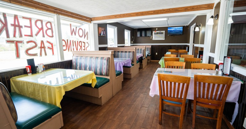 Interior with booths and tables, colorful tablecloths and large windows.