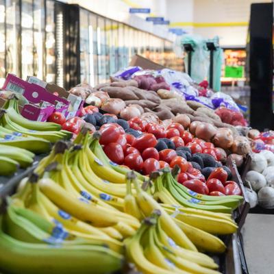 Fresh produce display with bananas, tomatoes, and potatoes in a supermarket.