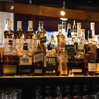 Whiskey bottles arranged on a bar shelf.