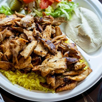Chicken Shawarma on a bed of saffron rice, served with hummus and salad.