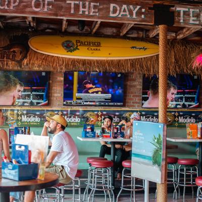 Interior shot with 3 TVs and a surfboard on the wall
