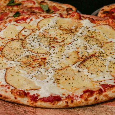 Pizza featuring sliced potatoes arranged over a base of mozzarella cheese.