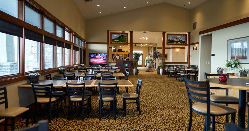 Interior, dining area, wooden tables and chairs, large windows, a TV on the wall