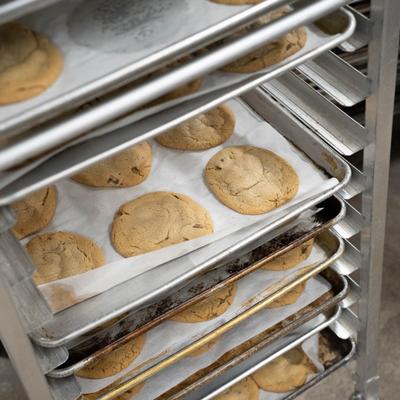 Metal rack filled with trays of freshly baked cookies on parchment paper.
