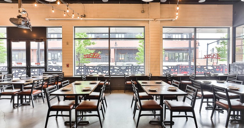 Interior, tables and chairs in seating area with large windows