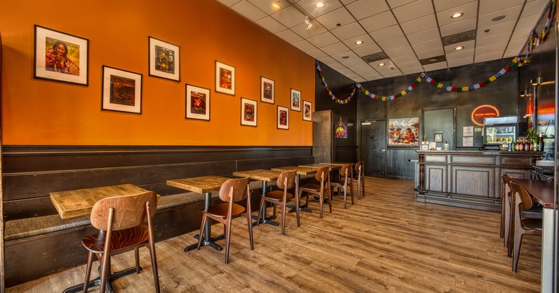 Interior, wide shot of a dining area, banquette bench with tables, wooden bar on the right