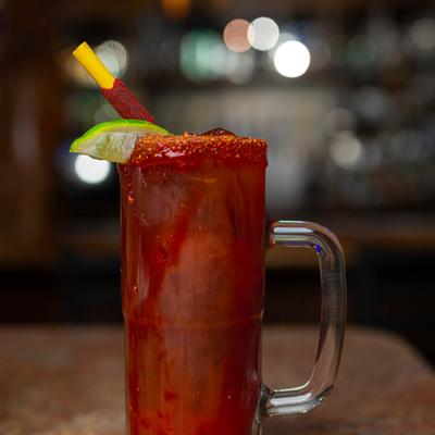 Michelada with a chili rim, lime, and a tamarind stick.