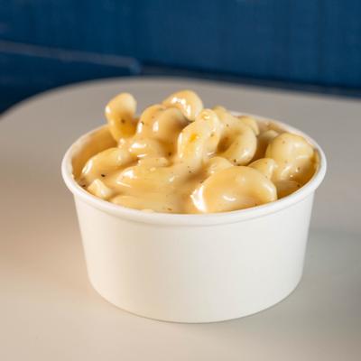 Creamy mac and cheese side in a takeout container.