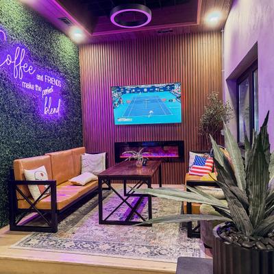Lounge seating with neon sign and a wall mounted television.