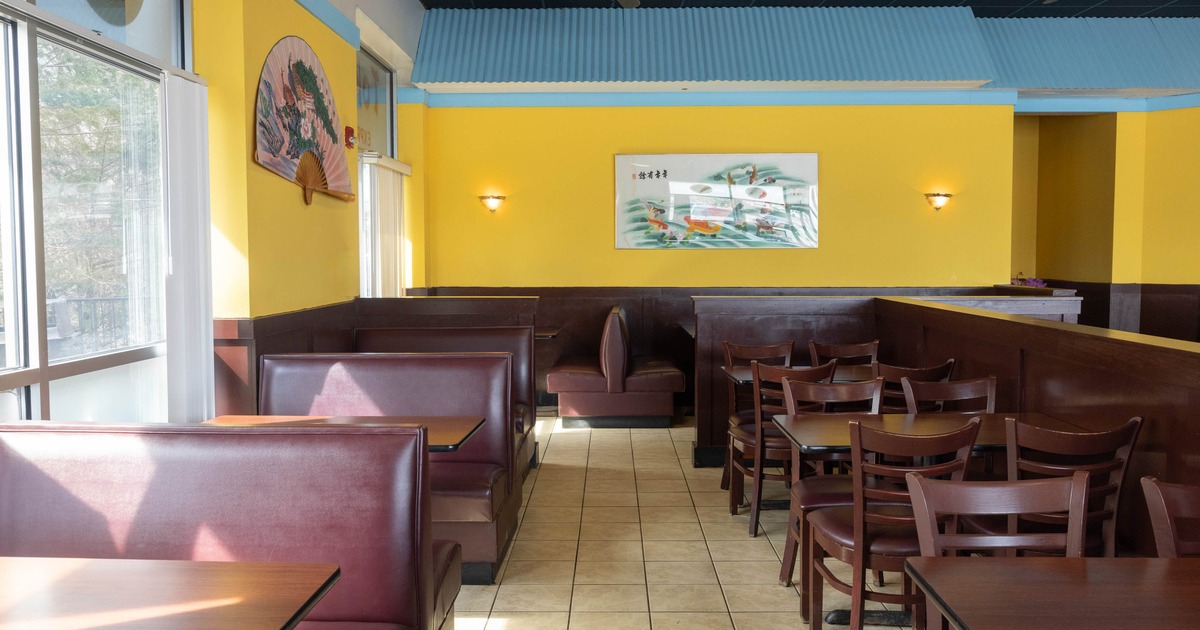 Restaurant interior with yellow walls, maroon booths, and wooden tables and chairs