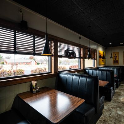 Interior with black leather booths, tables, and pendant lights.