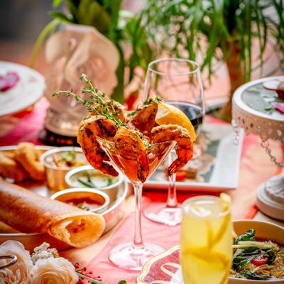 Shrimp cocktail surrounded by various dishes and drinks.