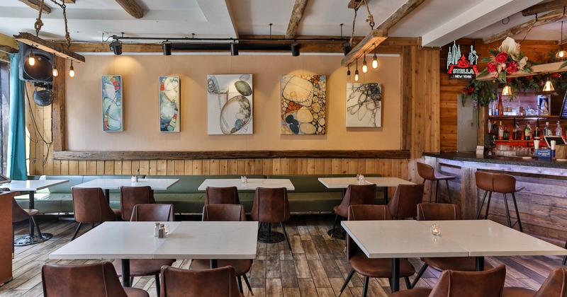 Interior, wooden beams, leather chairs, abstract art, and a bar