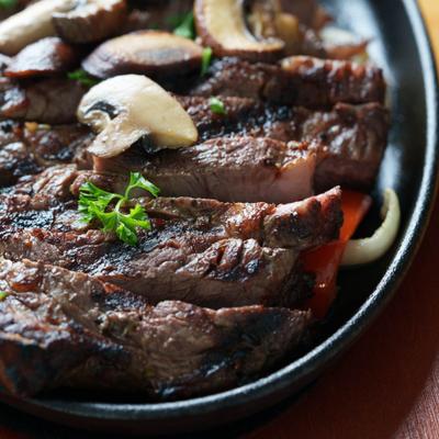 Sizzlin Steak served in a skillet with vegetables, close-up.