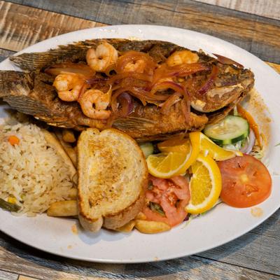 Mojarra al gusto served with shrimp, rice, vegetables, lemon, and toast.