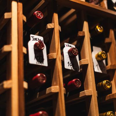 Close view of wooden wine rack with labeled bottles.