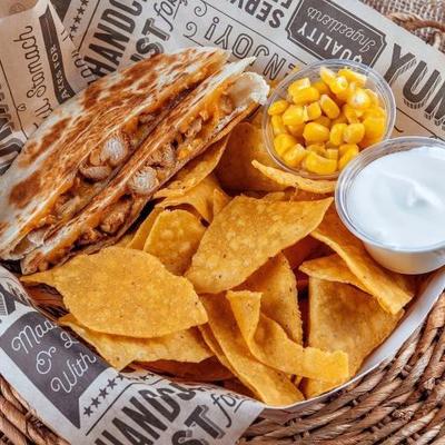 Quesadilla served with sides of nachos, sweet corn and sour creme.