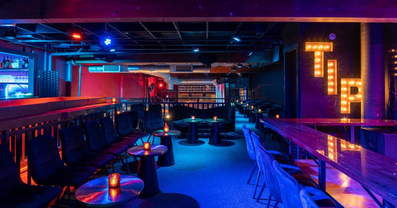 Upper floor, colorful lights, seating tables, and tables with bar stools