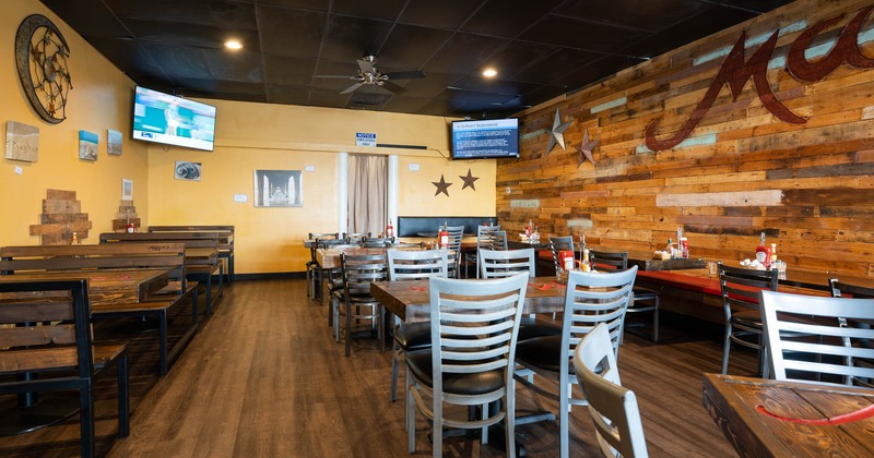 Interior, tables, chairs and wooden benches, tv screens in the corners