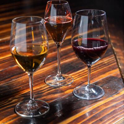 Three glasses of wine on a wooden table.