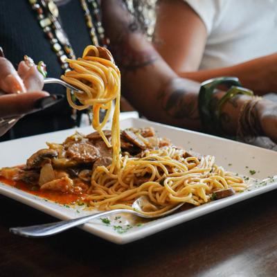 A woman enjoying her pasta, closeup on the dish.
