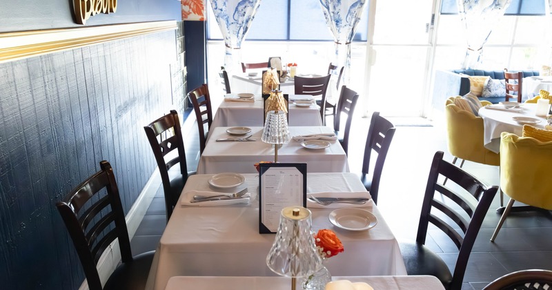 Interior with white tablecloths and elegant table settings under soft lighting