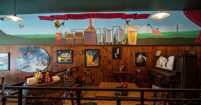 Interior, tables, chairs, piano with pictures on the wall