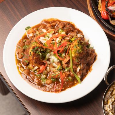 Two samosas served in a bowl of Indian chickpea curry.