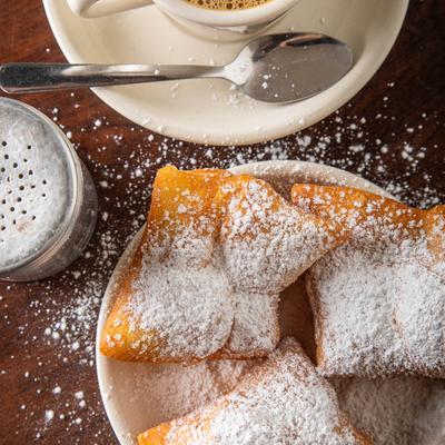 Beignets with powdered sugar, served with coffee.