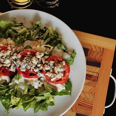 Fresh salad topped with tomatoes and crumbled cheese.