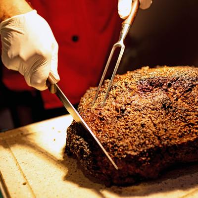 Chef slicing a large roasted beef brisket.