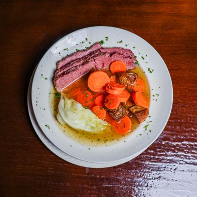Corned beef and cabbage with carrots on a round plate.