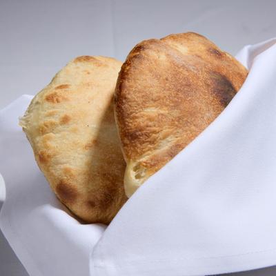 Two loafs of bread wrapped in a white cloth napkin.