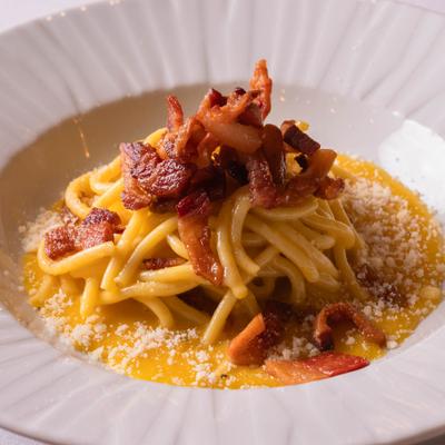 Plate of Bigoli Carbonara topped with guanciale.