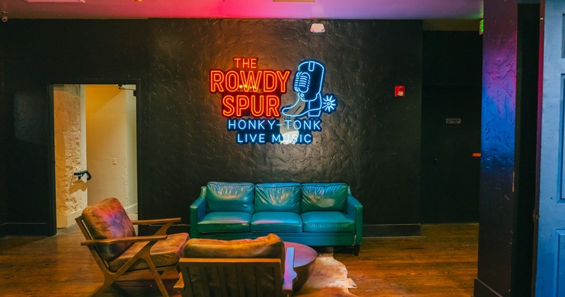 Interior, private seating area with leather couch and chairs, neon sign