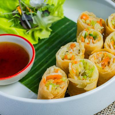 Crispy Thai spring rolls accompanied by sweet and sour sauce.