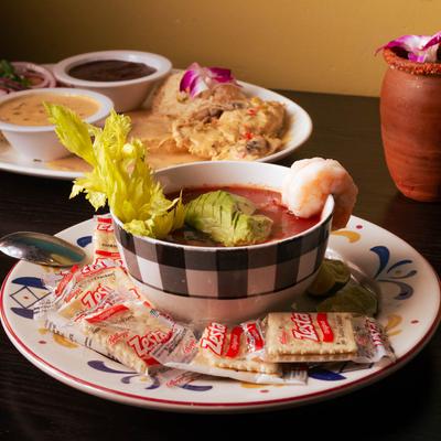 Shrimp ceviche, chicken in cream sauce with sides, accompanied with a clay mug cocktail.