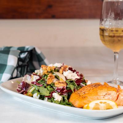 Tre Sorelle salad accompanied by salmon and white wine.