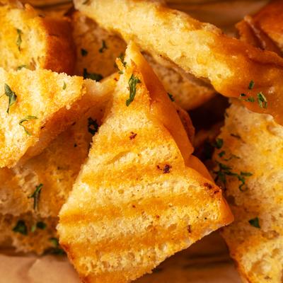 Garlic bread slices with herbs, close up.