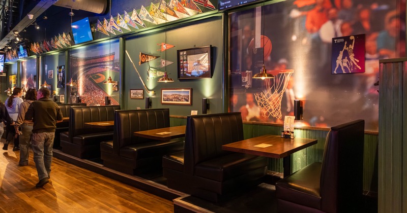 Interior with with dark leather booths and walls decorated with team pennants and murals