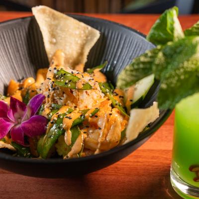 Sesame chile shrimp served with greens and chips in a bowl.